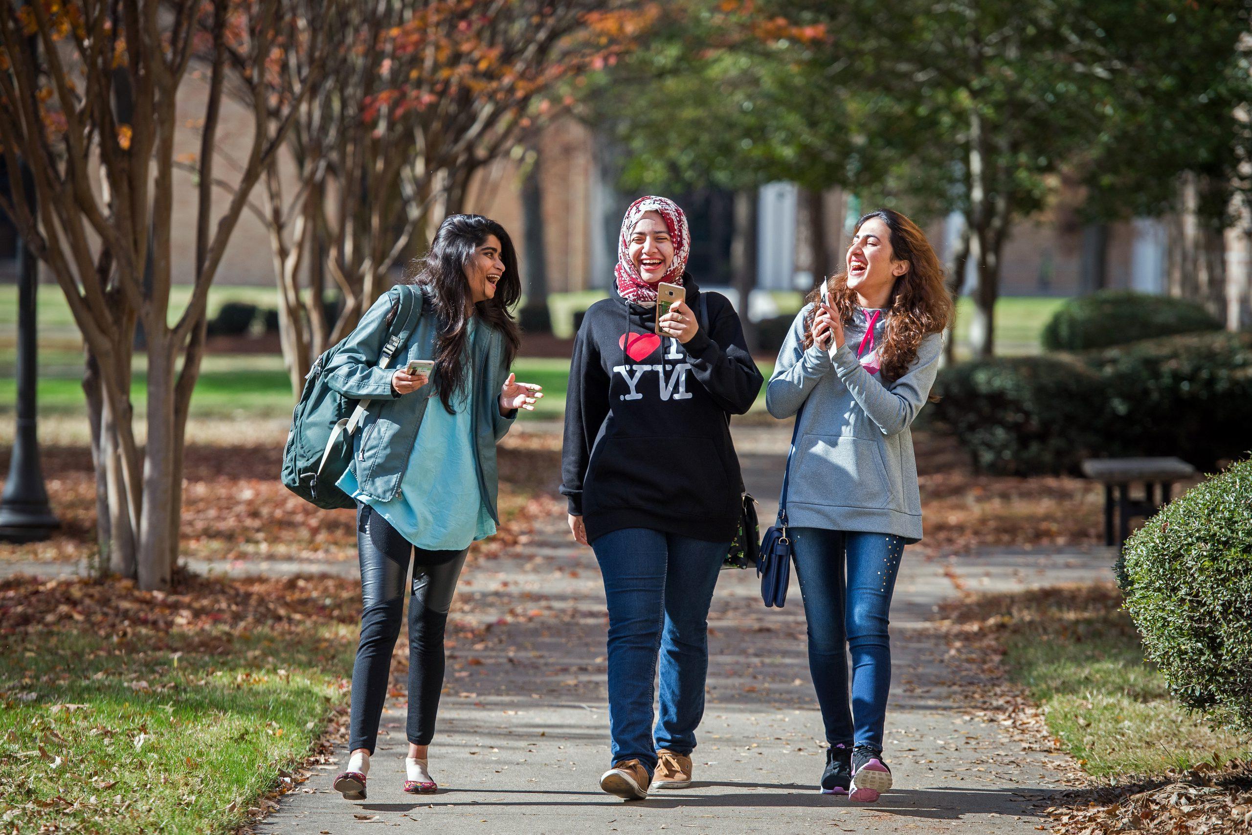 3 International students walking and having fun on campus.